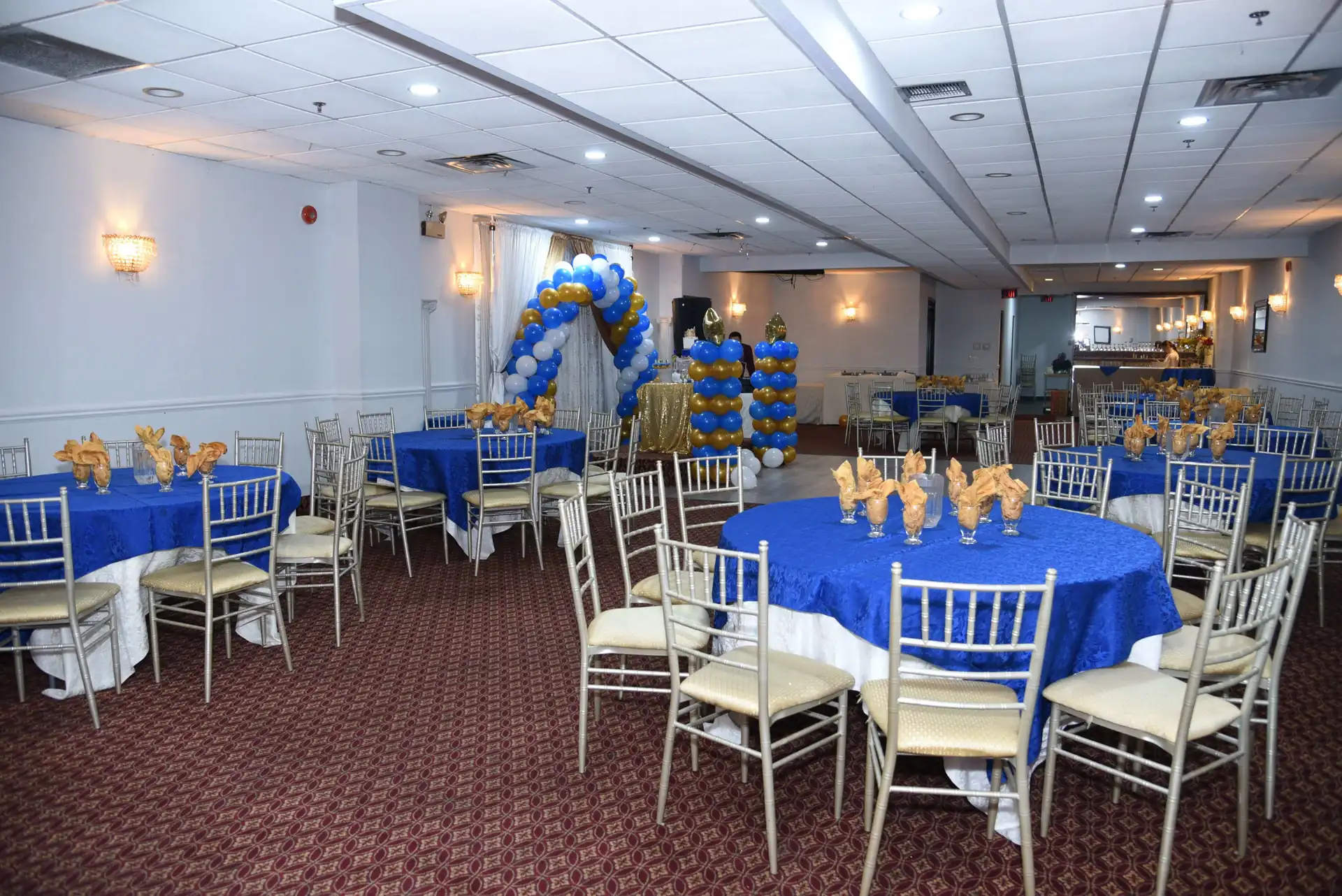 Blue and silver balloon decor against draped walls for a first birthday.