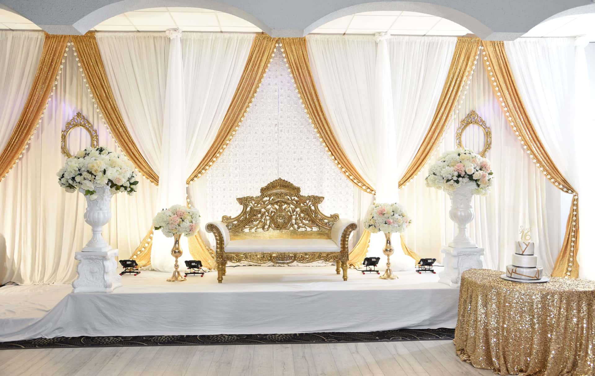 Wedding reception in the Grand Ballroom with gold chair covers, round tables and a lit head table.